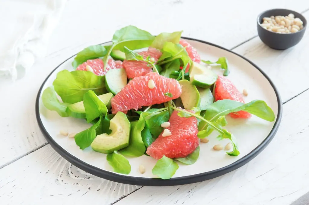 plato con semillas, aguacate troceado y hojas de frutos verdes