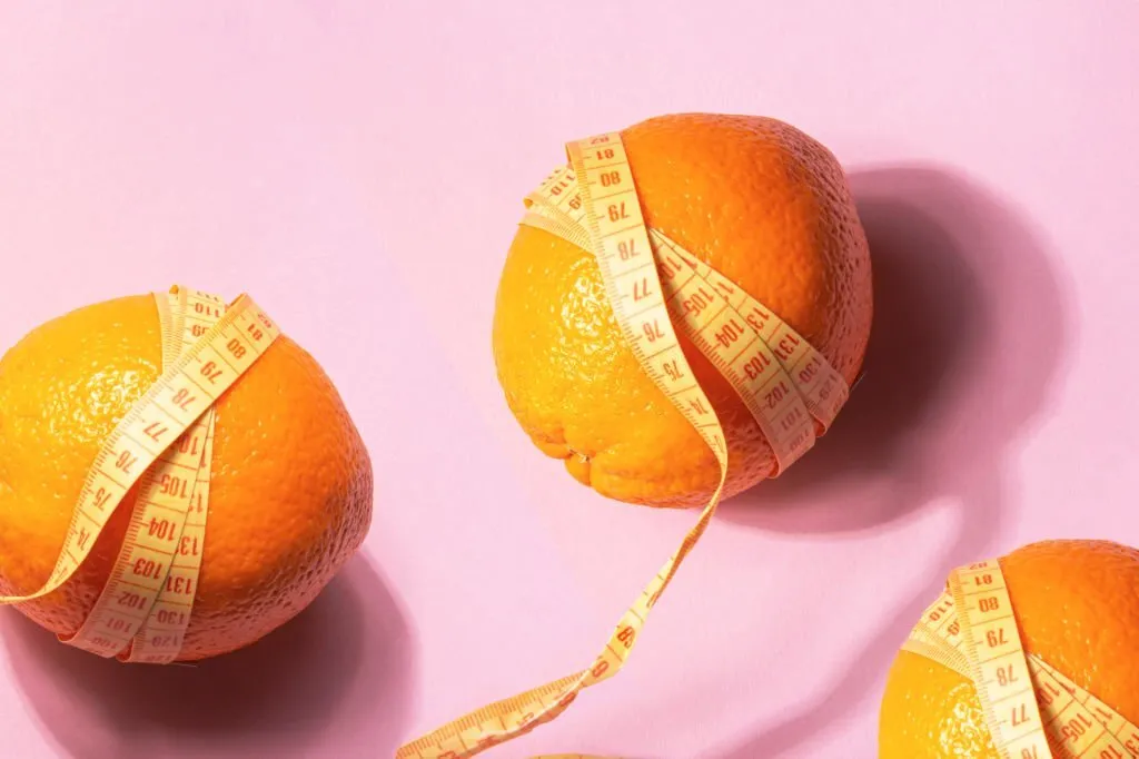 tres naranjas envueltas en cinta métrica