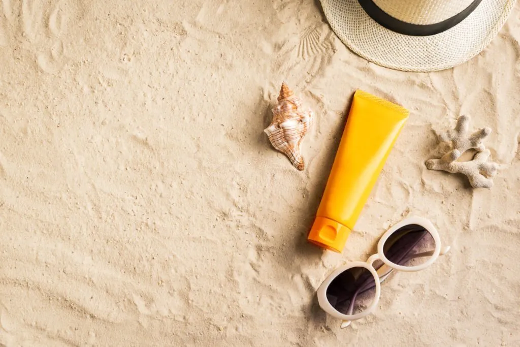protector solar y gafas de sol sobre la arena