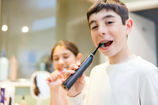 Niños divirtiéndose mientras se cepillan los dientes en un baño