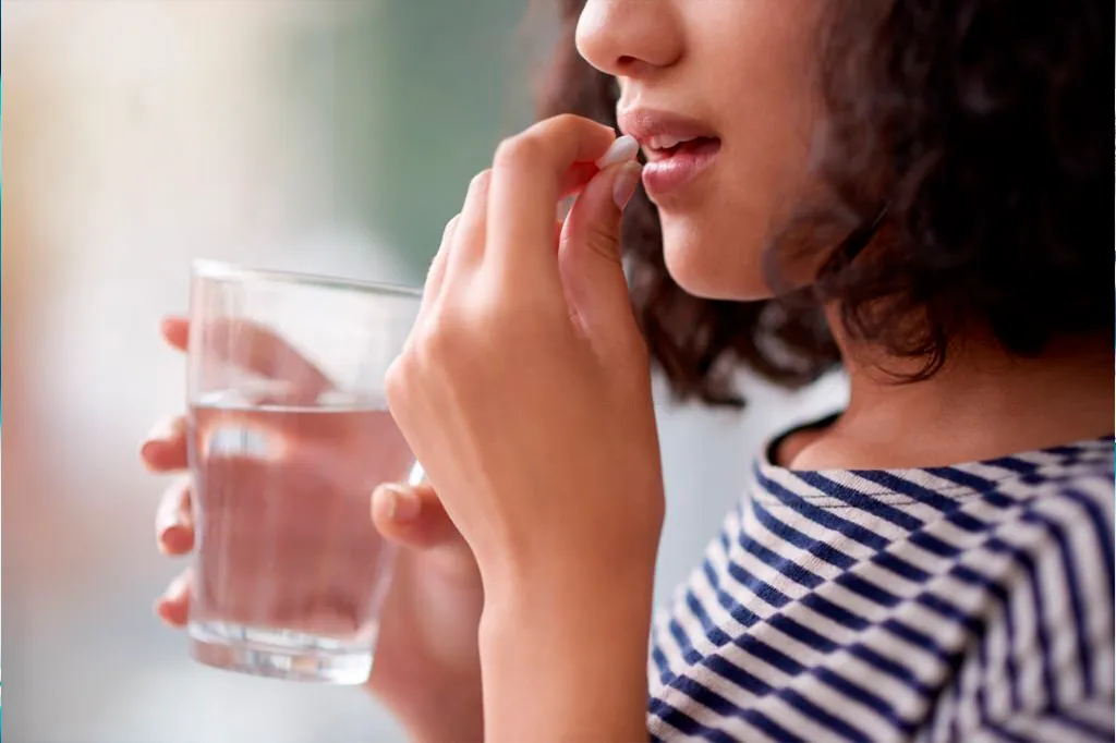 Mujer tomando un medicamento por vía oral